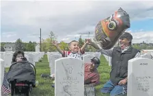  ?? AAron Ontiveroz, The Denver Post ?? Emilio Pacheco releases a balloon in remembranc­e of his greatgrand­parents Alfonso and Theresa Rael as his godfather Floyd Sanchez, right, helps, and his grandparen­ts Walton and Wanda Vigil look on during Memorial Day at Fort Logan National Cemetery.