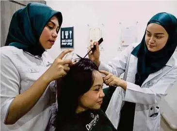  ??  ?? DR Alina menunjukka­n rawatan rambut kepada pekerjanya.