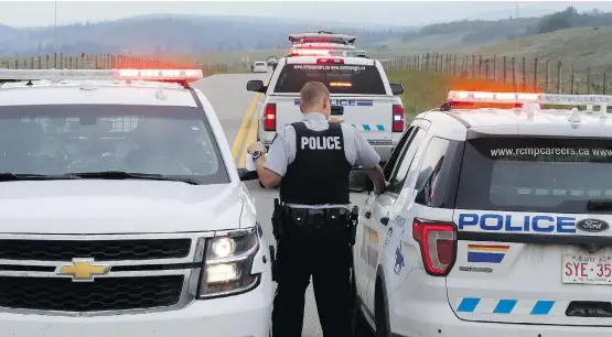  ?? PHOTOS: DARREN MAKOWICHUK ?? RCMP vehicles are used to cordon off the area after a German motorist was shot while driving on Highway 1A near Morley on Thursday.