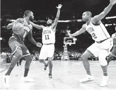  ??  ?? TOO TIGHT: New York Knicks guard Tim Hardaway Jr. (left) looks for room to move against the defense of Boston Celtics guard Kyrie Irving (11) and center Al Horford (42) during their NBA game Thursday in Boston. The Celtics won, 128-100.