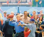  ?? J. SCOTT APPLEWHITE/ASSOCIATED PRESS ?? Then-President George W. Bush plays street football July 4, 2001, in Philadelph­ia during a block party intended to promote his faith-based initiative.