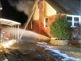  ?? EVAN BRANDT — DIGITAL FIRST MEDIA ?? Water shoots from a basement window of 119 E. 8th St. as firefighte­rs wipe out the last vestiges of a fire there Wednesday evening.