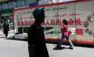  ?? ?? People walk past a sign with political propaganda in Kashgar, Xinjiang. Photograph: Pedro Pardo/AFP/Getty Images