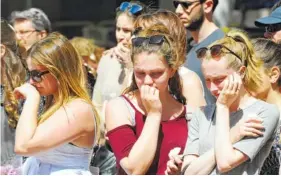  ?? THE ASSOCIATED PRESS ?? People react while visiting the flower tributes at St. Ann’s square in central Manchester, England, Friday. More than 20 people were killed in an explosion following an Ariana Grande concert at the Manchester Arena late Monday evening.