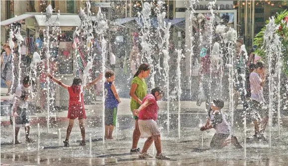  ??  ?? Children played in fountains to cope with high temperatur­es in Albania.