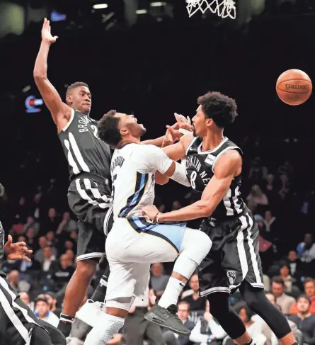  ??  ?? Memphis guard Andrew Harrison (5) loses the ball as he collides with Nets guards Caris LeVert, left, and Spencer Dinwiddie while driving to the basket on Monday in New York. KATHY WILLENS/AP