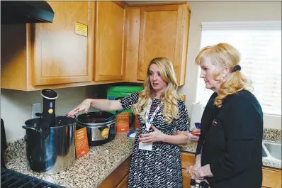  ?? PHOTOS BY WADE VANDERVORT ?? Cookbook author and food blogger Whitney Bond, left, demonstrat­es an Anova precision cooker, designed to slow cook food at low temperatur­es, to a visitor during a Cox Smart Home tour on April 5 in North Las Vegas. The Cox Smart Home by KB Home...