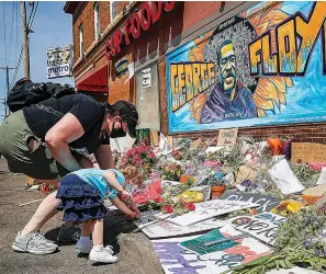  ?? Associated Press ?? ■ Jessica Knutson and her daughter Abigail, 3, place flowers at a memorial to George Floyd in Minneapoli­s. After a week of riots and looting over the loss of George Floyd, the Minneapoli­s black man who died after a police officer pressed his knee into his neck for more than eight minutes as he pleaded for air, parents are struggling to have the talk in this volatile moment, along with many others around race and racism.