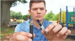  ?? ALLEN G. BREED/AP ?? Jay Jenkins holds a Yolo! brand CBD oil vape cartridge and a vape pen in Ninety Six, S.C. Jenkins says two hits from the vape put him in a coma.