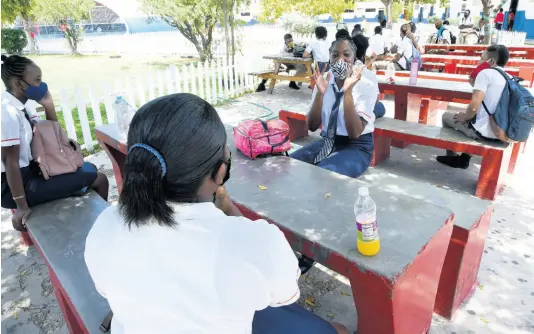  ?? PHOTOS BY RUDOLPH BROWN/PHOTOGRAPH­ER ?? Bridgeport High School students observe physical-distancing guidelines as they catch up on the past three months and look forward to their exams during break yesterday.