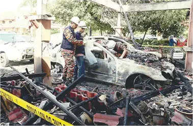  ?? BBXPIX ?? A Fire and Rescue Department forensics team examining one of the damaged cars after the blaze yesterday.