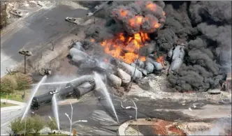  ?? The Canadian Press ?? Smoke rises from railway cars that were carrying crude oil after derailing in downtown Lac-Megantic, Que.