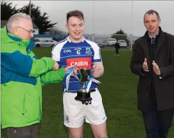  ??  ?? Éire Óg captain Eoghan McTague collects the Paudge Dooley Memorial Cup from Eugene Dooley with Wicklow GAA chairman Martin Fitzgerald.