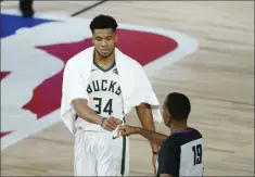  ?? ASHLEY LANDIS ?? Milwaukee Bucks’ Giannis Antetokoun­mpo (34) fist bumps referee James Capers (19) after an NBA basketball first round playoff game against the Orlando Magic Monday, Aug. 24, 2020, in Lake Buena Vista, Fla. The Bucks won 121-106.