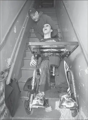  ?? JOHN KENNEY  THE GAZETTE ?? Philip Paraskevop­oulos lifts his son, Philip, 14, up the stairs at their home in Verdun. The stolen van was the boy’s main means of getting to school and other places.