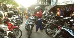  ?? UMAR WIRAHADI/JAWA POS ?? RAUP REZEKI: Jukir menarik uang parkir motor di area Pasar Gresik Jalan Samanhudi kemarin.