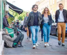  ?? — AFP ?? This file photo taken on July 23, 2017 shows a group of people walking past homeless people on Broadway Market in east London.