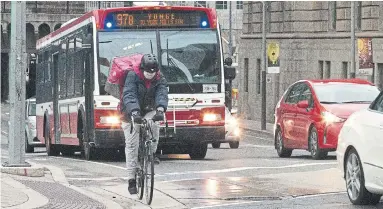  ?? KELSEY WILSON TORONTO STAR ?? A Foodora delivery courier wears a face mask as a precaution­ary measure en route near Front and Yonge streets.