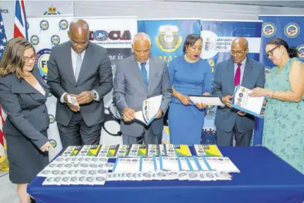  ?? ?? Analysing printed training material donated to local law enforcemen­t agencies are (from left) Amy Tachco, deputy chief of mission at the US Embassy in Kingston; Deputy Commission­er of Police Fitz Bailey; Colonel Desmond Edwards, director general of MOCA; Velma Ricketts Walker, CEO of Jamaica Customs Agency; Selvin Hay, director general of the FID; and Colleen Falconer, programme manager at the FCDO.