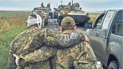  ?? KOSTIANTYN LIBEROV/AP FILE ?? A Ukrainian soldier helps a wounded fellow soldier on the road in the freed territory in the Kharkiv region on Sept. 12. Despite a year of killing, destructio­n and loss, Ukraine is still here.