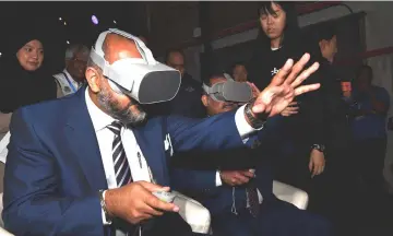  ??  ?? Gobind tries on the virtual reality applicatio­n after the launch in George Town. — Bernama photo