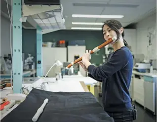  ?? (AFP photo) ?? Musician Mina Jang plays a wooden transverse flute next to its white 3D-printing replica at the music lab of Musee de la Musique in Paris on January 17, 2020