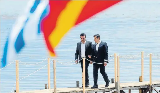  ?? MAJA ZLATEVSKA / AFP ?? El primer ministre macedoni, Zoran Zaev (esquerra), i el grec, Alexis Tsipras, caminen junts sobre un pont al llac fronterer de Prespa