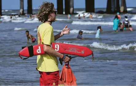  ?? Yi-Chin Lee / Staff photograph­er ?? Lifeguard Baxter Wright calls swimmers to stay away from the rip currents near Pleasure Pier in Galveston. A red flag warning was in place for strong rip currents. Officials suggested that children should remain along the surf line.