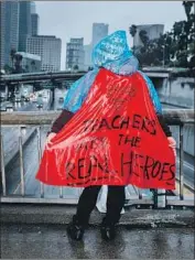 ?? Marcus Yam Los Angeles Times ?? A SUPPORTER of striking Los Angeles teachers wears a Superman cape and rain gear above the 110 Freeway in downtown Los Angeles on Monday.