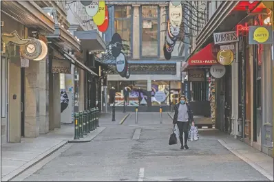  ?? (AP/Asanka Brendon Ratnayake) ?? A lone shopper walks Wednesday down the usually busy Degraves Street laneway famed for its cafes and coffee during lockdown in Melbourne, Australia.