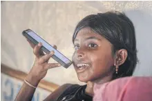  ??  ?? The daughter of Rohingya refugee Arofa Khatun, who tried to migrate with her two daughters to Malaysia to see her husband, speaks on the phone with her father at a shelter in the Kutupalong camp.