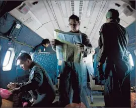  ?? Mohd Rasfan AFP/Getty Images ?? A MEMBER of the Malaysian air force consults a map aboard a military aircraft as the crew takes part in the search for a Boeing 777 that disappeare­d last weekend with 239 people aboard. Thirteen countries are involved in the effort.