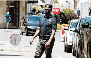  ?? ANTONIO CALANNI/AP ?? A border police officer wears a mask to prevent the spread of the virus Wednesday as cars cross into Italy at the Italian-Swiss border in Ponte Chiasso.