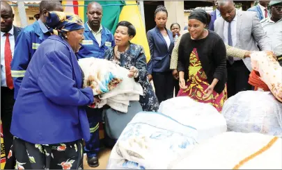  ??  ?? First Lady Auxillia Mnangagwa hands over blankets and Christmas food hampers to Gogo Susan Musendeki (left) of Rose of Sharon while Mashonalan­d East Provincial Affairs Minister Apollonia Munzvereng­i (right) looks on at Marondera Childcare Society yesterday. — (Picture by Memory Mangombe)