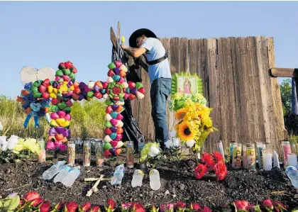  ?? Photo / AP ?? Roberto Marquez of Dallas adds a flower to a makeshift memorial at the site where officials found dozens of people dead in an abandoned semitraile­r.
