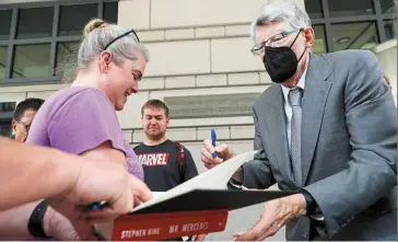  ?? — Reuters ?? Favourable testimony: Stephen King signs autographs as he leaves the US District Court in Washington. The celebrated novelist is siding with the government in an antitrust case against a publisher merger.