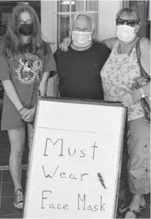  ?? DAVID JALA CAPE BRETON POST ■ ?? Shopkeeper Albert Miles is flanked by customers Chloe Cooke, left, and Florence Cooke, at the entrance to Ed’s Books and More on Charlotte Street in Sydney on Sunday. All three were wearing masks in compliance with a provincial directive that came into effect on July 31 that makes facial coverings compulsory in public and commercial places.