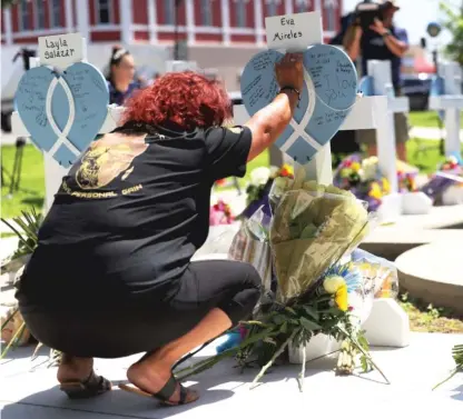  ?? MICHAEL M. SANTIAGO/GETTY IMAGES ?? A mourner places her hand on a memorial for a victim of the mass shooting at Robb Elementary School in Uvalde Town Square on May 26.