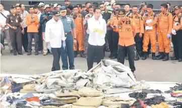  ??  ?? Indonesian President Joko Widodo (front, second right), Indonesia’s Minister of Transporta­tion Budi Karya Sumadi (front, left) and Syaugi (front, right) tour the operations centre as recovered debris from the ill-fated Lion Air flight JT 610 are laid out at a port in northern Jakarta.