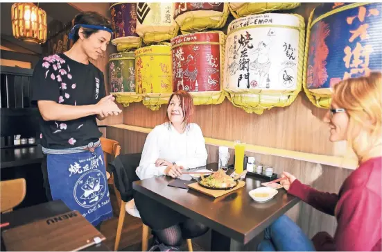  ??  ?? Barkeeper Yoshihara Inoue serviert im „Yaki-The-Emon“Victoria Paesen (l.) und Julia Deisinger Drinks.