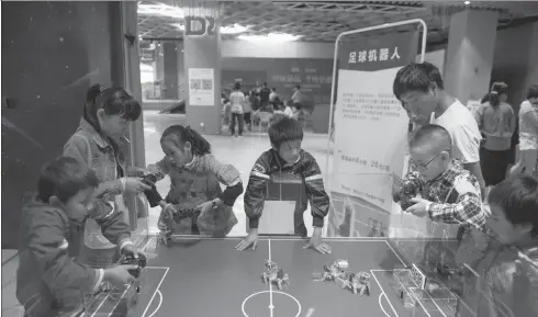  ?? HU CHAO / XINHUA ?? Children control robot table soccer players at a competitio­n during a robot carnival and summer youth camp in Kunming, capital of Southwest China’s Yunnan Province, on July 15. More than 50 robots featured in education, entertainm­ent, service and...