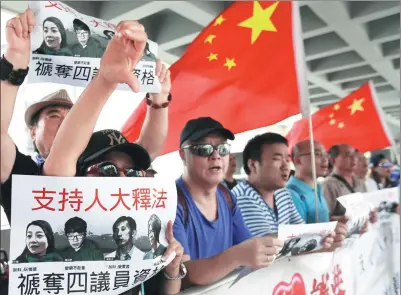  ?? ROY LIU / CHINA DAILY ?? Residents outside the high court hold placards and shout slogans on Friday to support the disqualifi­cation of four lawmakers who did not follow the requiremen­ts when they took their oaths to serve on the Legislativ­e Council in October last year.