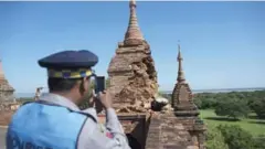  ?? YE AUNG THU/AFP ?? A police officer takes a picture at the damaged, ancient Htilominlo Temple after a 6.8 magnitude earthquake hit Bagan.