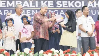  ?? — Bernama photo ?? Ahmad Zahid handing out a helmet to a recipient at the Northern Corridor Economic Region (NCER) mini showcase programme in Bagan Datuk yesterday.