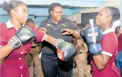  ?? ASHLEY ANGUIN ?? Jasmine Graham (centre), AMBC woman heavyweigh­t boxing champion of the Caribbean, demonstrat­es boxing techniques to Herbert Morrison Technical High School’s Ashari Buckeridge (left) and Feandrea Nelson during a boxing workshop programme held at the school last Thursday.