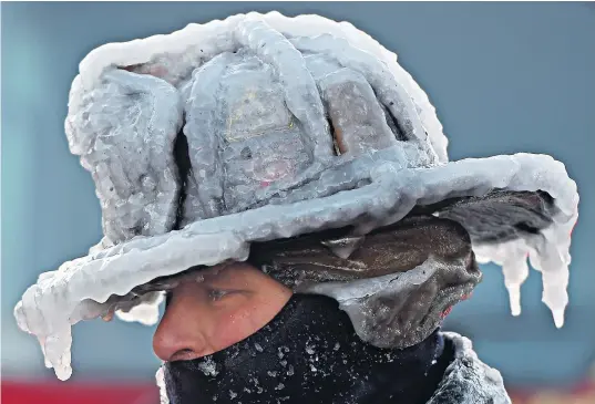  ??  ?? Firefighte­r Bobby Lehman’s helmet is covered in thick ice after water used to fight a house fire in Nahant, Massachuse­tts, froze instantly on equipment, causing problems dousing the flames