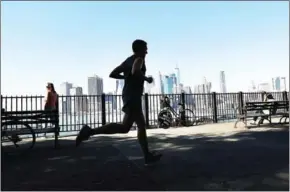  ?? GETTY IMAGES/AFP SPENCER PLATT/ ?? A man jogs along a promanade on a summer-like day on October 18.