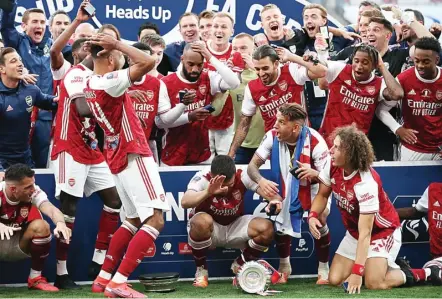  ?? CATHERINE IVILL/POOL/AP ?? OOOPS…: Striker Arsenal Pierre-Emerick Aubameyang (tiga dari kiri) disaksikan rekan setimnya menjatuhka­n trofi Piala FA di Stadion Wembley kemarin (2/8).