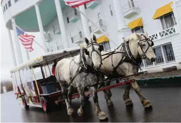  ?? ELLEN CREAGER Detroit Free Press/TNS ?? Horses pull a carriage on the grounds of The Grand Hotel on Mackinac Island, Michigan.