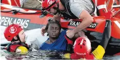  ?? Foto: Paul Barrena, afp ?? Mit vereinten Kräften ziehen die Helfer die völlig erschöpfte Josefa aus dem Meer. Für zwei weitere Flüchtling­e kam die Hilfe zu spät.